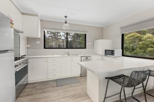 een keuken met witte kasten en een groot raam bij Beach House at Quiet Corner in Adventure Bay