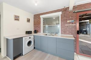 een keuken met een spoelbak en een wasmachine bij Beach House at Quiet Corner in Adventure Bay +6 foto's