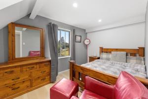 een slaapkamer met een bed en een spiegel en rode stoelen bij Beach House at Quiet Corner in Adventure Bay