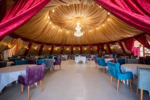 GuemarPalm Garden Souf的一个大帐篷，里面有桌椅，装饰着红色和金色的图案。