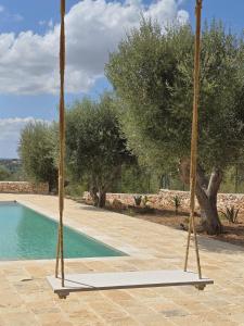 奥斯图尼Borgo Cervarolo的一个游泳池，周围有两棵棕榈树和一个秋千