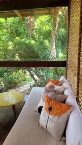 a bed with pillows on it in front of a window at Pousada Raízes na Vila de Barra Grande in Marau