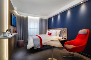 a hotel room with a bed and a red chair at Holiday Inn Express - Saarbrücken by IHG in Saarbrücken