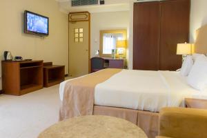 a hotel room with two beds and a television at Al Qurum Resort in Muscat