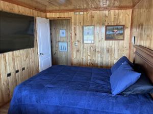 a bedroom with a blue bed in a wooden room at Chiloé,Curaco de Velez casa de veraneo in Curaco de Velez
