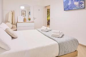 a white bedroom with a bed with towels on it at Dimora Esclusiva Borgo Opifici - Lollo House Subiaco in Subiaco