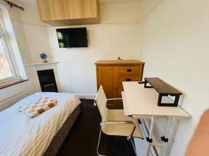 ein Schlafzimmer mit einem Bett, einem Schreibtisch und einem Tisch in der Unterkunft The Norbury Hill Residence in West Norwood