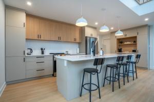 a kitchen with a large white island with bar stools at Le Greenwood 2 - Sauna - Spa - Mountain View in Saint-Faustin