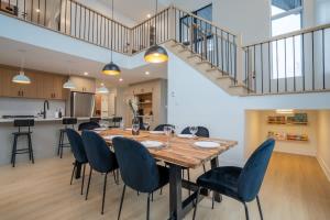 a dining room with a wooden table and blue chairs at Le Greenwood 2 - Sauna - Spa - Mountain View in Saint-Faustin