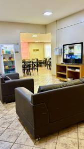 a living room with couches and a large screen tv at Hotel Nacional Service in Goiânia