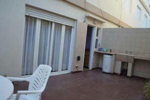 eine Terrasse mit einem weißen Stuhl neben einem Gebäude in der Unterkunft Lucaya in Miramar