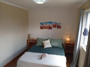 a small bedroom with a bed with green pillows at El Vagón in Sierra de la Ventana