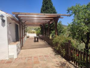 a wooden pergola with a bench on a walkway at Casa Cuesta Gato in Sedella