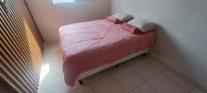ein kleines Bett mit rosa Bettwäsche und Kissen in einem Zimmer in der Unterkunft Apartamento mobiliado próximo Unesc em Criciúma in Criciúma + 2 Fotos