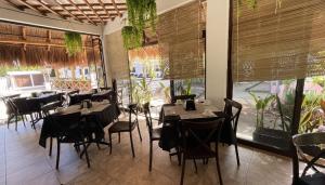 a restaurant with black tables and chairs and windows at Villas Palmar Holbox in Holbox Island