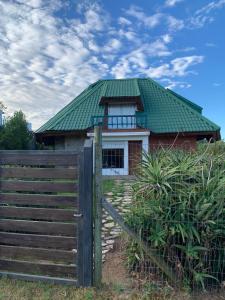 uma casa com um telhado verde e uma cerca em Pucara del Este em Punta del Este