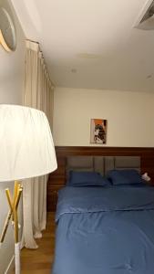 Schlafzimmer mit einem Bett mit blauer Bettwäsche und einer Lampe in der Unterkunft شقه فندقيه غرفة نوم وغرفة معيشه in Al Kharj