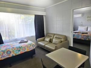 Tarawera River Lodge Motel في Kawerau: غرفة بها أريكة وسرير وطاولة +107 صور