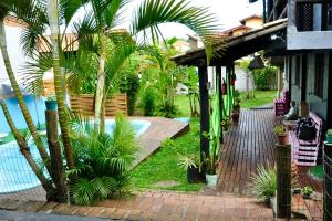 un complexe avec piscine et palmiers dans l'établissement Pousada pantera do rosa, à Imbituba