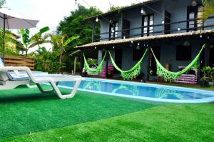 une maison avec une piscine, une chaise et un parasol dans l'établissement Pousada pantera do rosa, à Imbituba