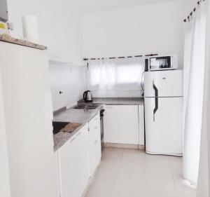 a white kitchen with a refrigerator and white cabinets at Nuestras raíces 1 in Villa Carlos Paz