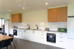 a kitchen with white cabinets and a wooden table at Lake Colac Holiday Park in Colac