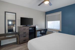 a bedroom with a bed and a desk with a television at HOM Hotel Gainesville, SureStay Collection by Best Western in Gainesville