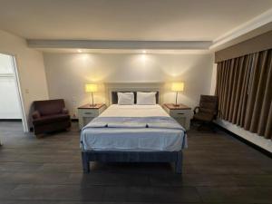 a bedroom with a bed and two chairs and two lamps at Florentine Motel And Studio in Bell