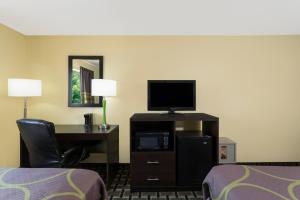 a hotel room with a desk with a television and a bed at Super 8 by Wyndham Marietta in Marietta