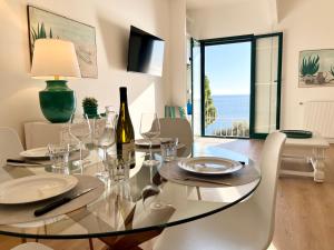 a dining room with a glass table with a bottle of wine at Mimosa Seafront Apartment - Free parking Wi-Fi in Varazze