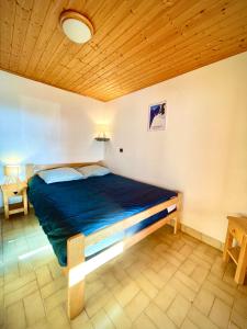 un lit dans une chambre avec un plafond en bois dans l'établissement CHARMIEUX appartement en chalet typique, au Grand-Bornand