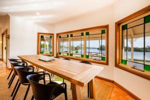 a dining room with a table and chairs and windows at Crystal Palms - Oceanstays - Riverside in Yamba