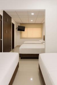 1 dormitorio con 3 camas y TV de pantalla plana en The Royalty Lite, en Guayaquil