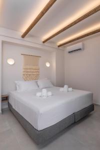 een witte slaapkamer met een groot bed met witte lakens bij Avaton Boutique Suites in Vrachonisída touArchangélou +3 foto's