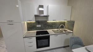 una piccola cucina con armadi bianchi e lavandino di Green Apartman a Veternik