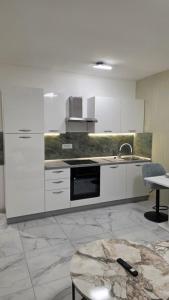 una cucina con mobili bianchi, un lavandino e un tavolo di Green Apartman a Veternik Altre 8 foto