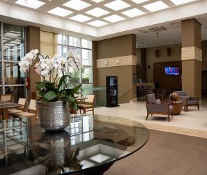 eine Lobby mit einem Glastisch mit einer Vase aus Blumen in der Unterkunft Flat Sofisticado no Jade Hotel Home Office in Brasilia