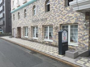 ein Backsteingebäude mit Parkuhr davor in der Unterkunft Creston Hotel in Iwaki
