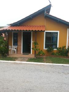 Casa amarilla con porche y mesa en Hospedaria da Josilene, en Florianópolis
