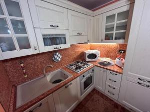 Una cocina con gabinetes blancos, un fregadero y una estufa. en Bernina House, en Chiesa in Valmalenco 20 fotos más