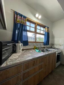 a kitchen with a counter with a sink and a window at Rosa Mosqueta Esquel in Esquel +3 photos