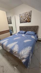 a bedroom with a bed with a blue comforter at Flower Apartman in Veternik +21 photos