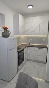 a white kitchen with a sink and a refrigerator at Flower Apartman in Veternik