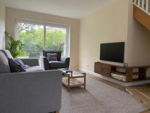 a living room with a couch and a flat screen tv at Comfortable Homestay by Earith Lakes in Earith