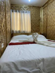 Dos cisnes hechos de toallas en una cama en The Tribe Apartment, en Port Barton