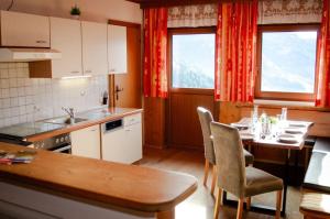 a kitchen with a table and chairs and two windows at Schlickhütte in Grossarl