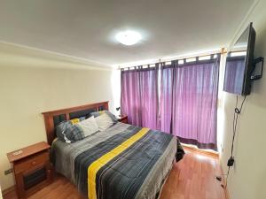 Schlafzimmer mit einem Bett und einem Fenster mit lila Vorhängen in der Unterkunft Excellent apartment, view and quiet atmosphere in Viña del Mar