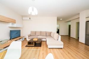 a living room with a white couch and a tv at Poseidon Nest - 2BR, 360 Sea View, Office in Durrës