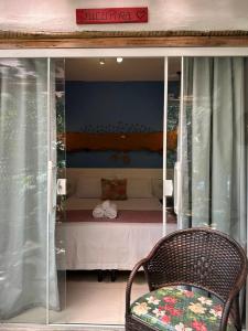 a bedroom with a bed and a chair in a window at Aruana Suites com Cafe da manha,Piscina, Reserva Natural da Sapiranga 5km da Vila de Praia do Forte in Castelo da Tôrre