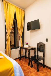 - une chambre avec un bureau, un lit et une télévision dans l'établissement Hotel Villa Luna, à San Juan La Laguna